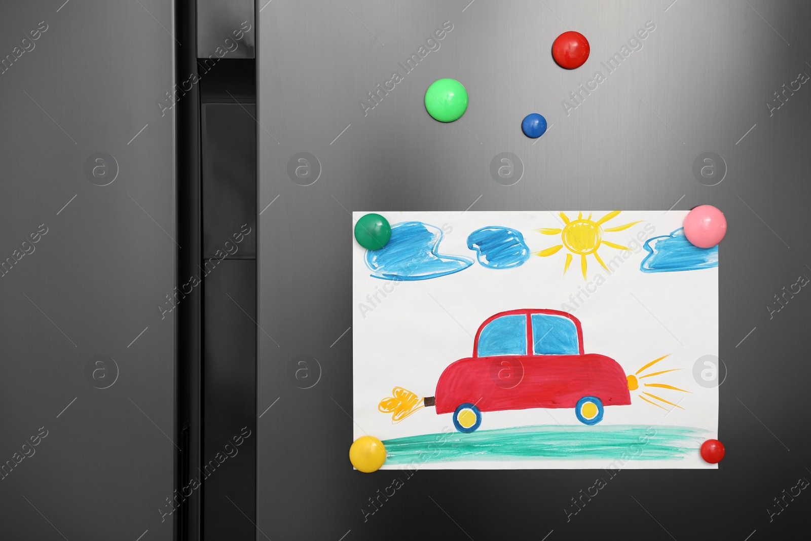 Photo of Modern refrigerator with child's drawing and magnets