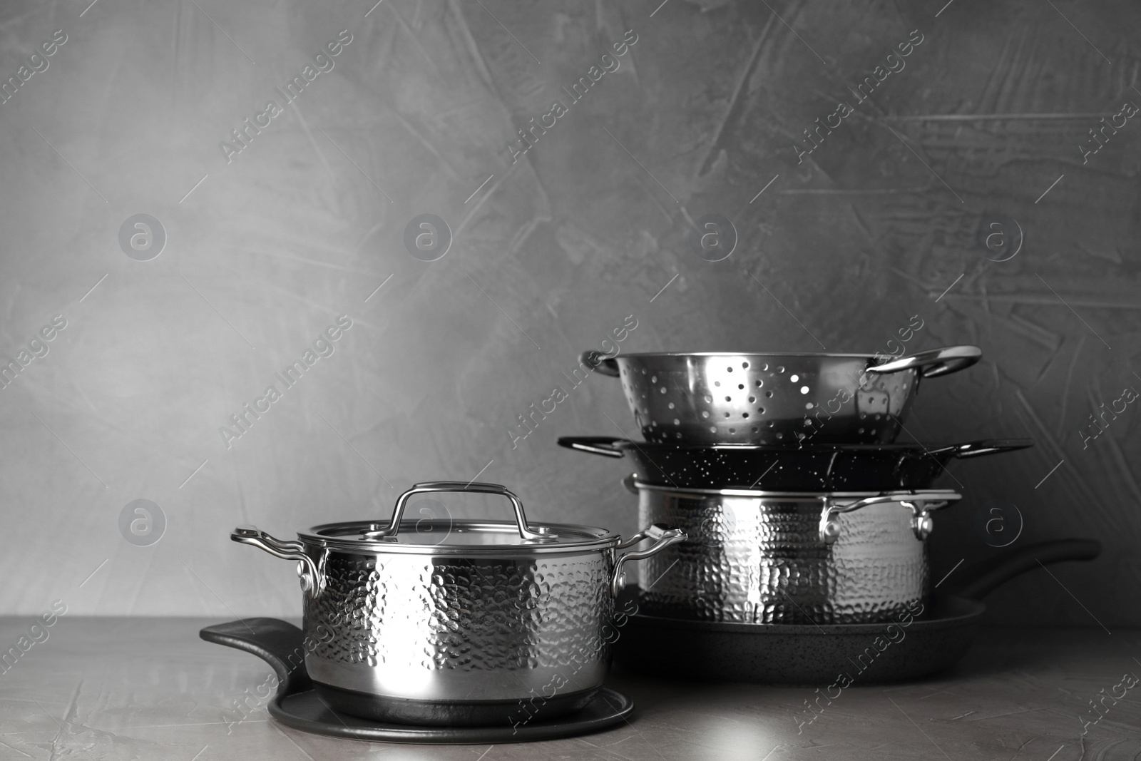 Photo of Set of clean cookware on table against grey background. Space for text