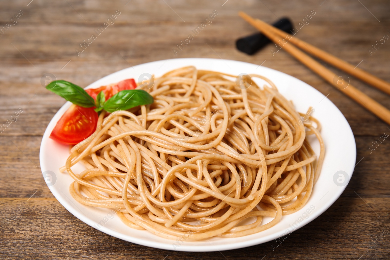 Photo of Tasty buckwheat noodles served on wooden table