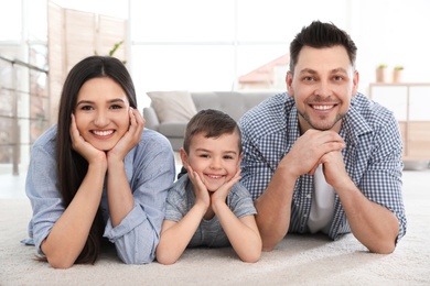 Photo of Happy couple and their son lying on carpet at home. Family time