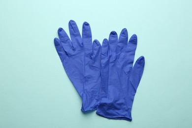 Photo of Pair of medical gloves on light blue background, flat lay