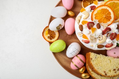 Photo of Traditional Easter cake with dried fruits and painted eggs on white table, top view. Space for text