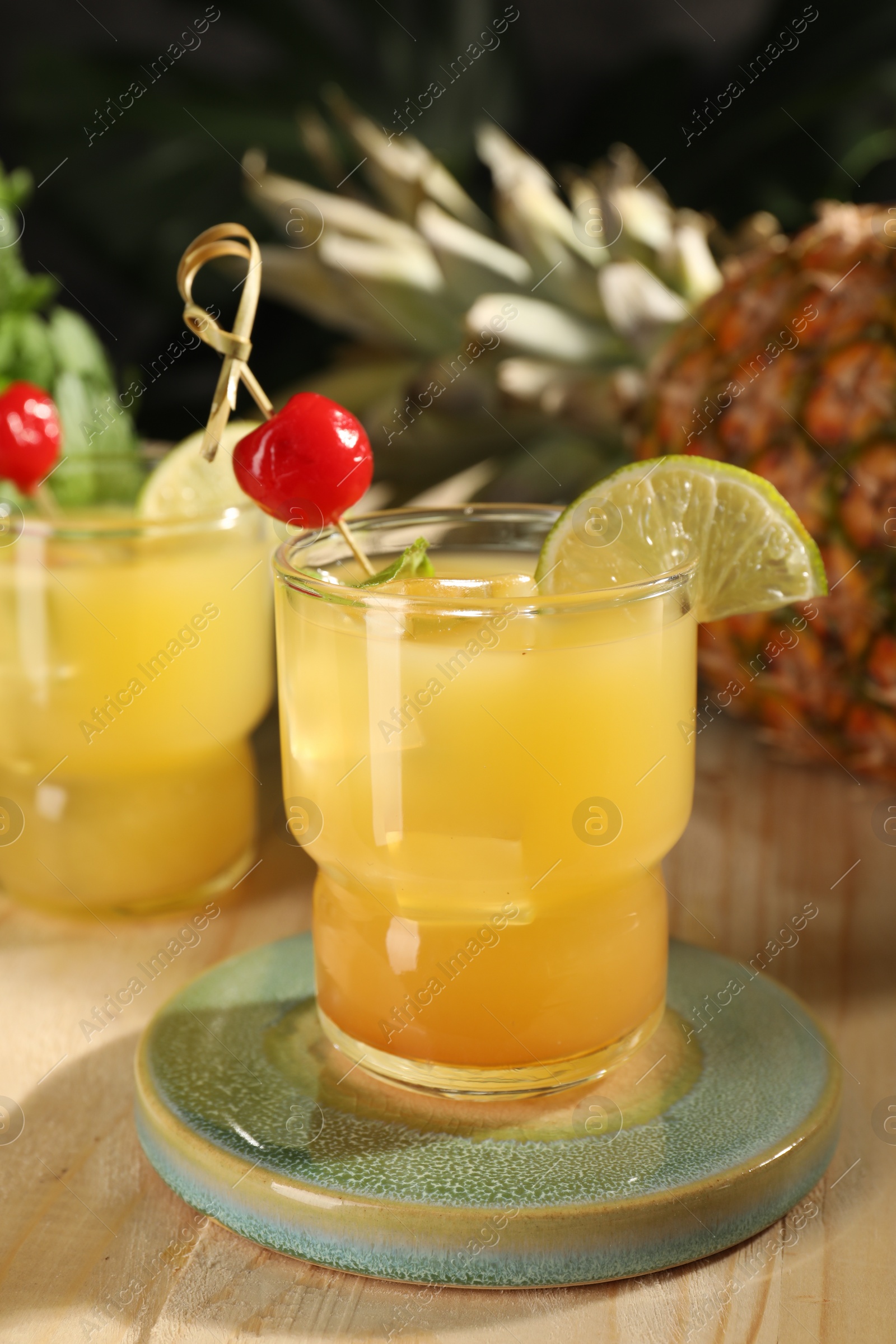 Photo of Tasty pineapple cocktail with cherry and lime on wooden table