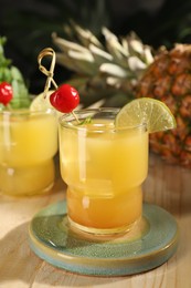 Tasty pineapple cocktail with cherry and lime on wooden table