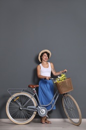 Portrait of beautiful young woman with bicycle near color wall