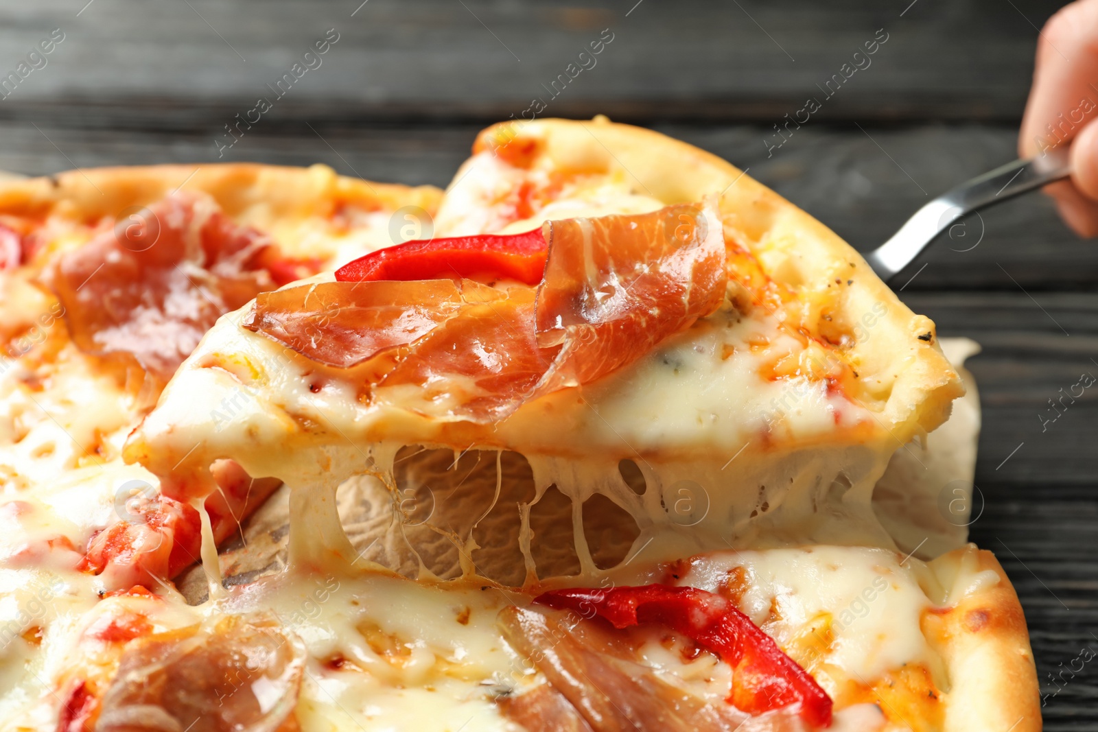 Photo of Woman holding shovel with slice of delicious hot pizza over table, closeup