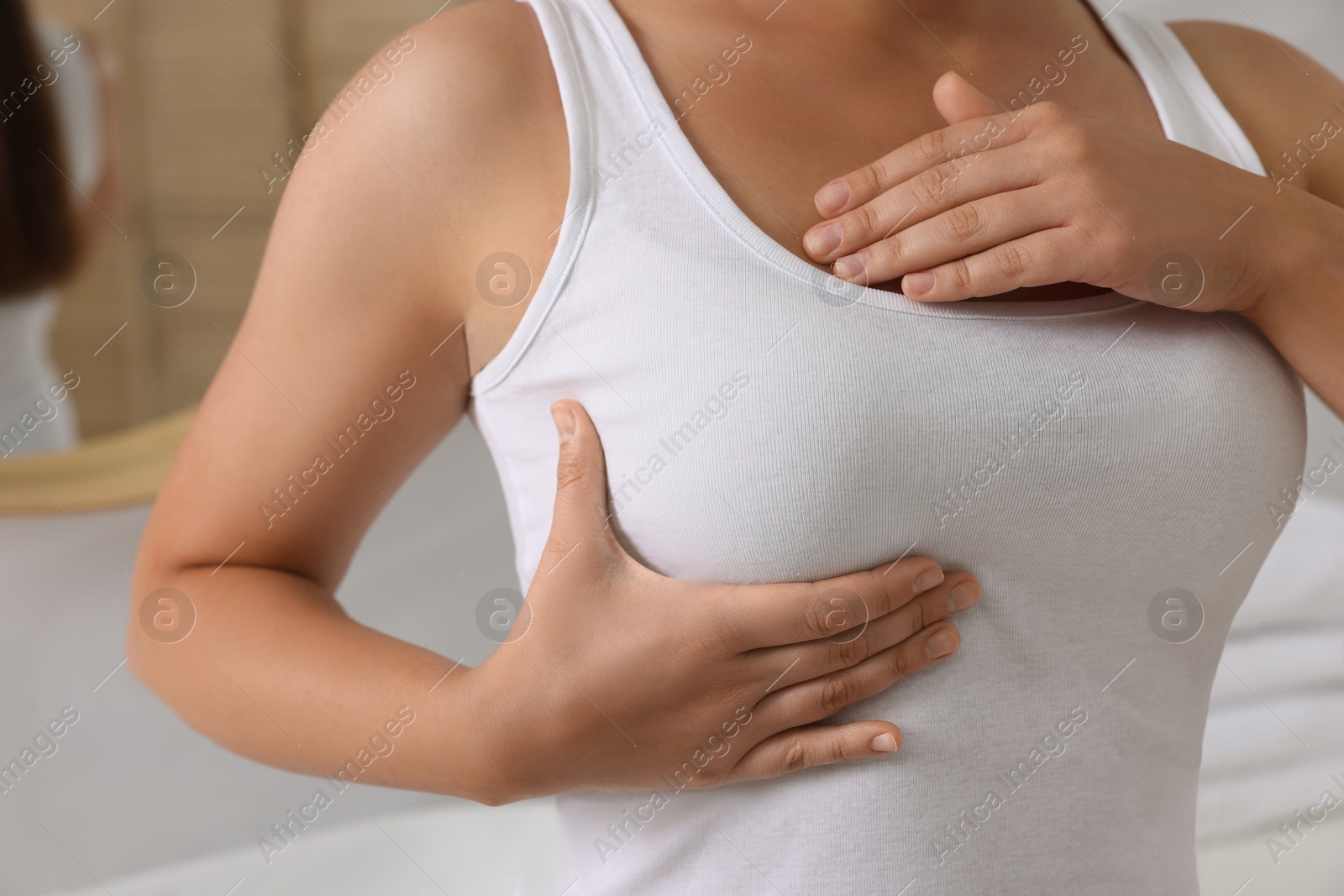 Photo of Woman doing breast self-examination in bathroom, closeup