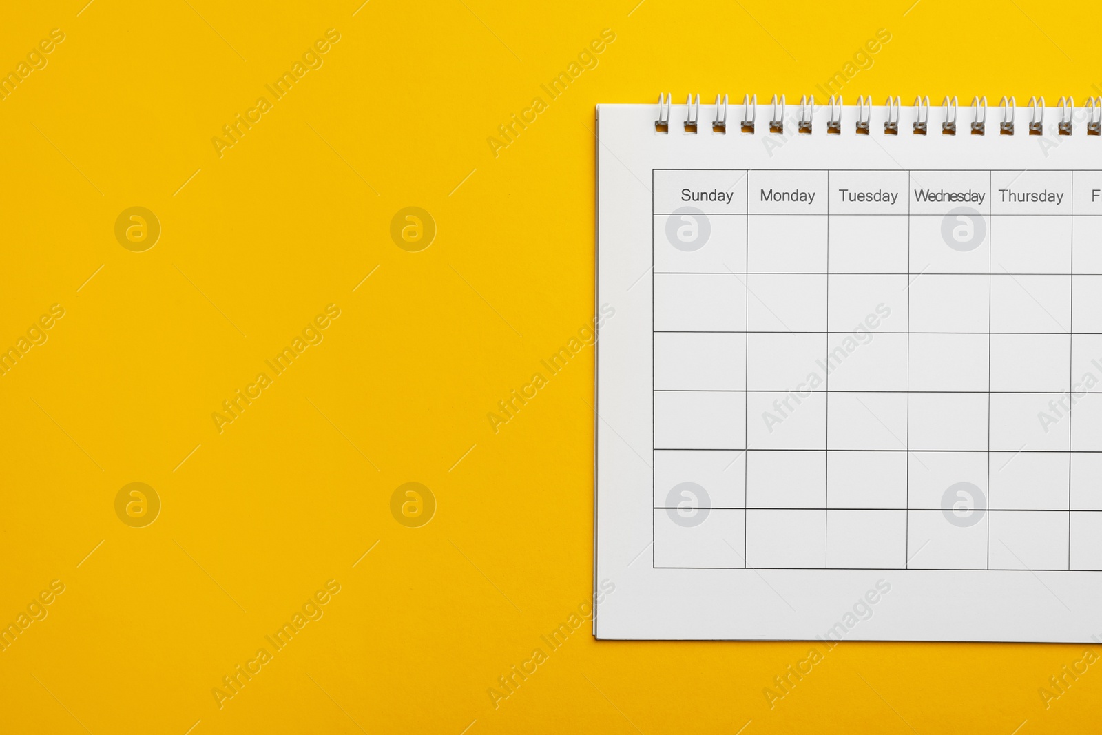 Photo of Blank calendar on yellow background, top view. Space for text