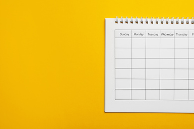 Blank calendar on yellow background, top view. Space for text