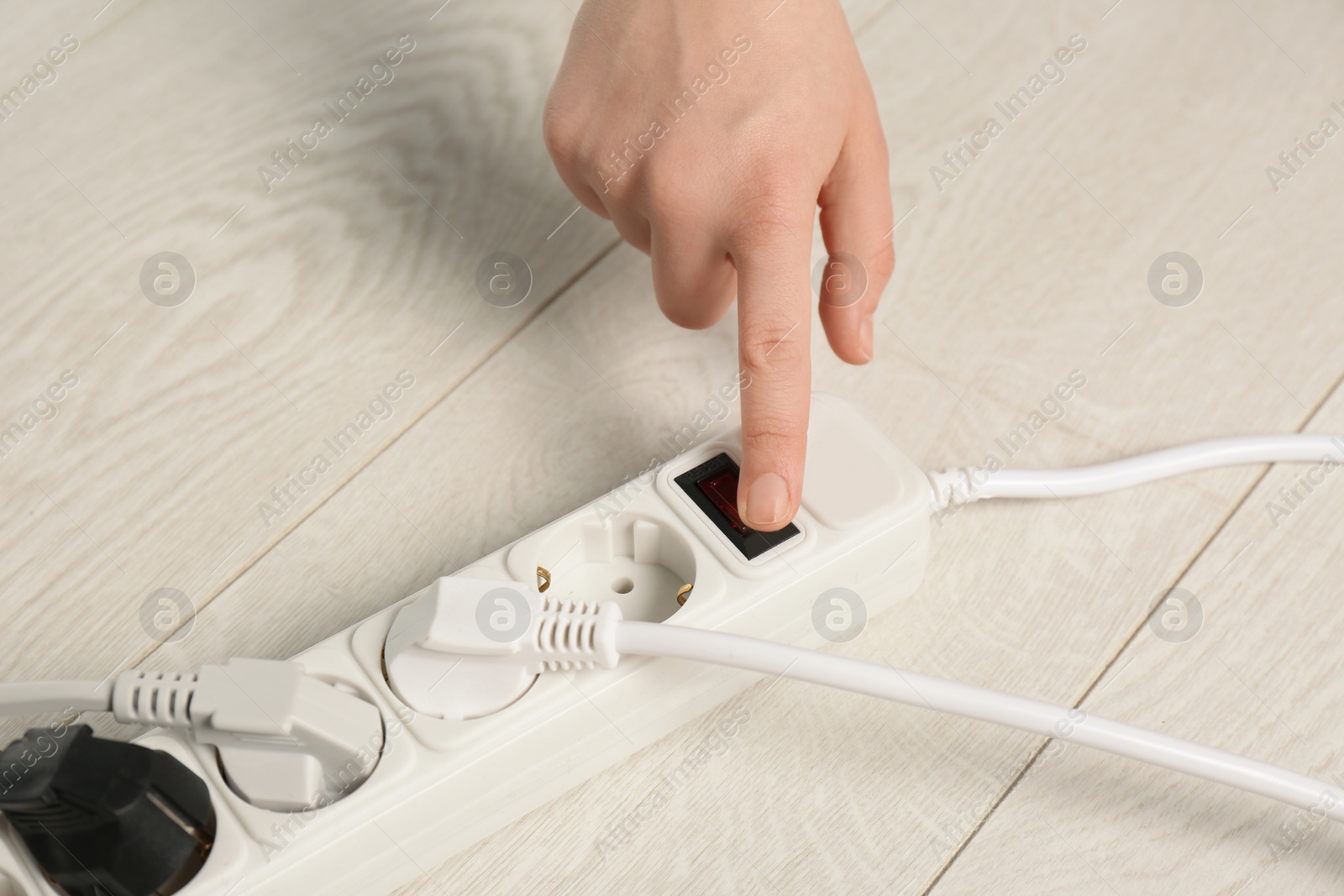 Photo of Woman pressing power button of extension cord on floor, closeup. Electrician's professional equipment