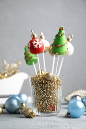 Photo of Delicious Christmas themed cake pops and festive decor on wooden table against grey background