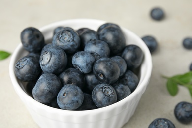 Bowl with tasty blueberries on light table, closeup