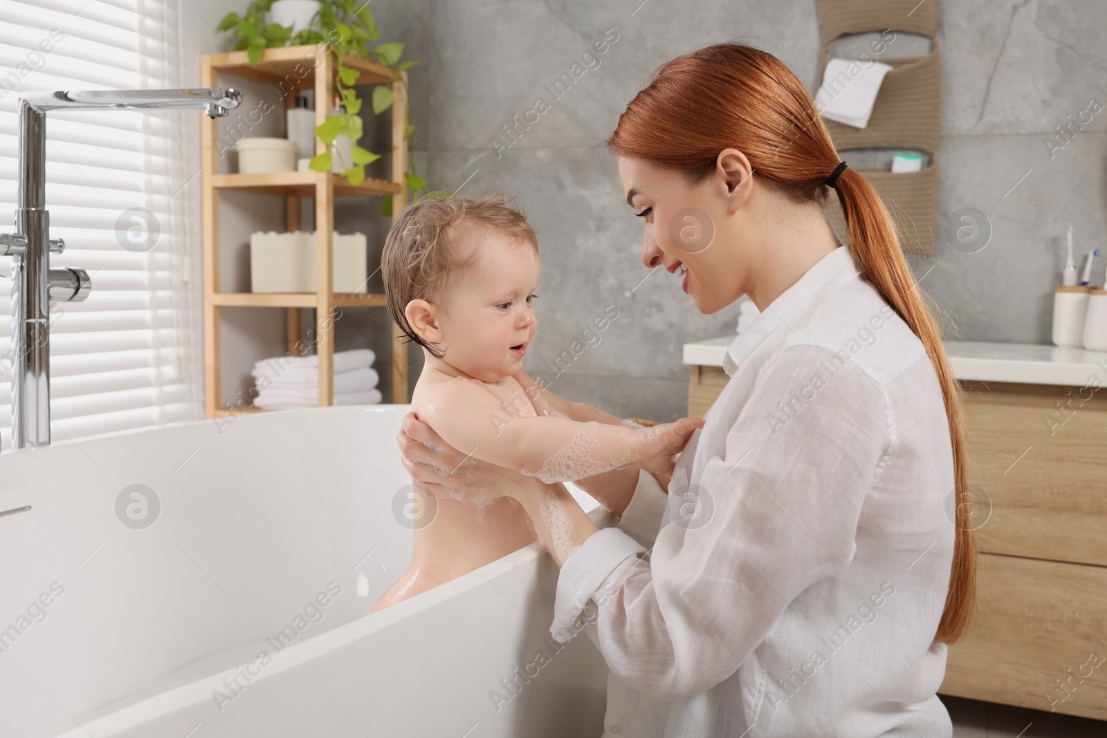 Photo of Mother washing her little baby in tub at home