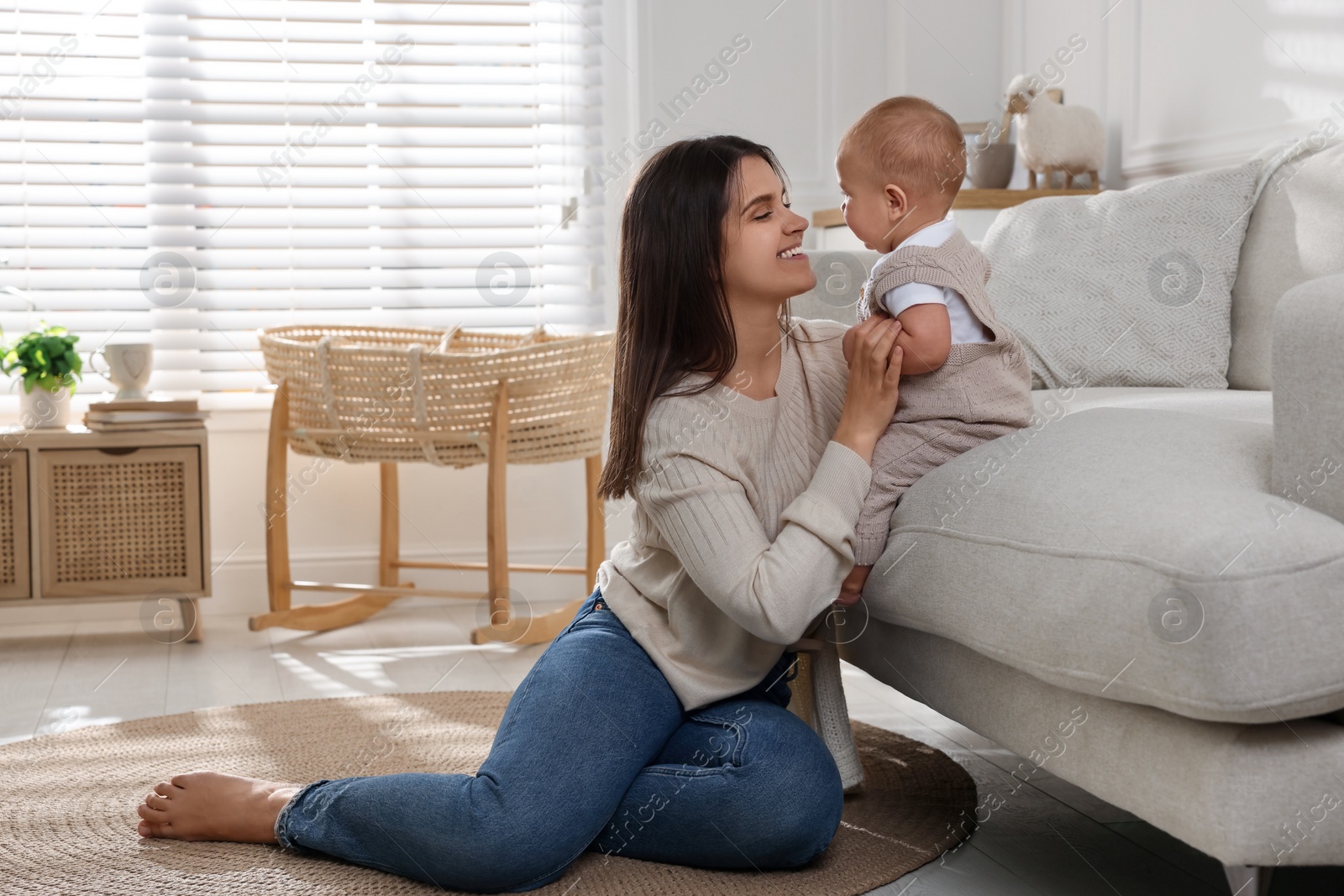 Photo of Happy young mother with her baby in living room. Space for text