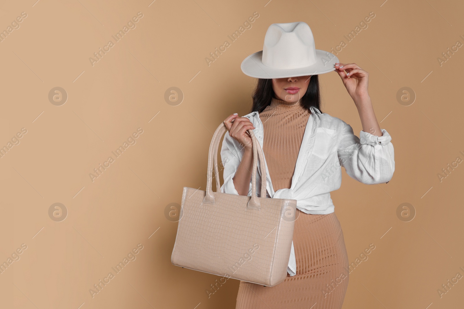 Photo of Young woman with stylish bag on beige background, space for text