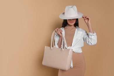 Photo of Young woman with stylish bag on beige background, space for text