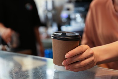 Photo of Barista putting takeaway paper cup with coffee on countertop in cafe. Space for text