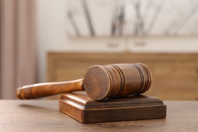 Photo of Wooden gavel and sound block on table indoors, closeup