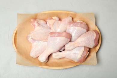 Photo of Plate with raw chicken wings and drumsticks on gray background, top view. Fresh meat