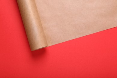 Photo of Roll of wrapping paper on red background, top view. Space for text