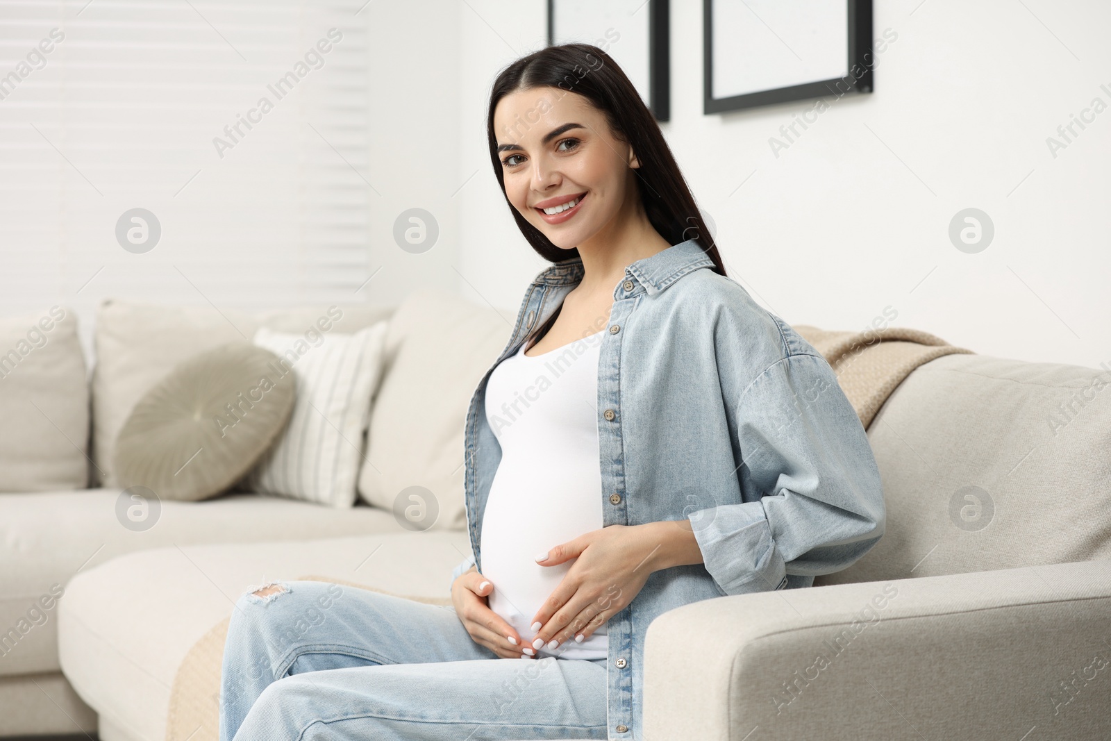 Photo of Happy pregnant woman on sofa at home