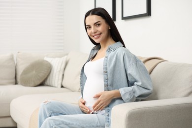 Happy pregnant woman on sofa at home