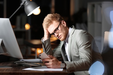Photo of Tired young businessman working in office alone at night