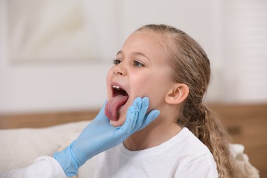 Photo of Doctor in gloves examining girl`s oral cavity indoors