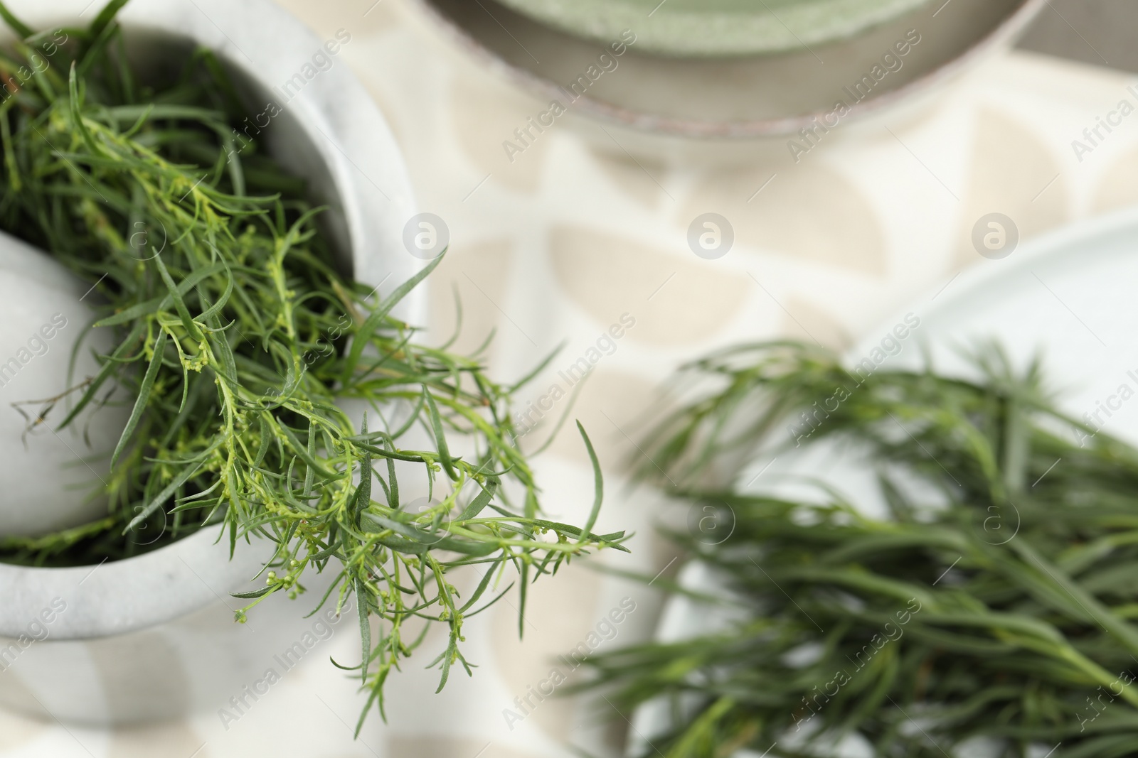 Photo of Plate and mortar with fresh tarragon leaves on table, above view
