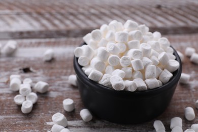 Bowl with delicious marshmallows on wooden table, closeup