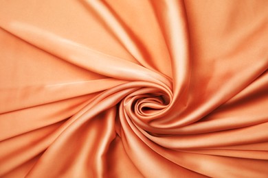 Delicate orange silk fabric as background, top view