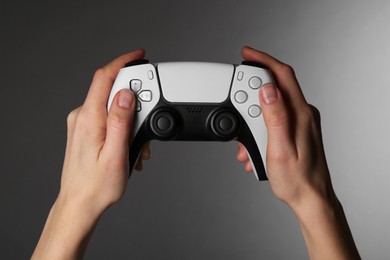 Woman using game controller on grey background, closeup