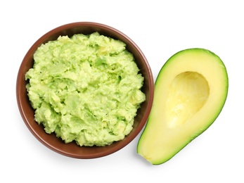 Photo of Bowl of tasty guacamole and cut avocado on white background, top view