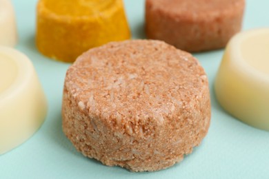 Photo of Group of solid shampoo bars on turquoise table, closeup. Hair care