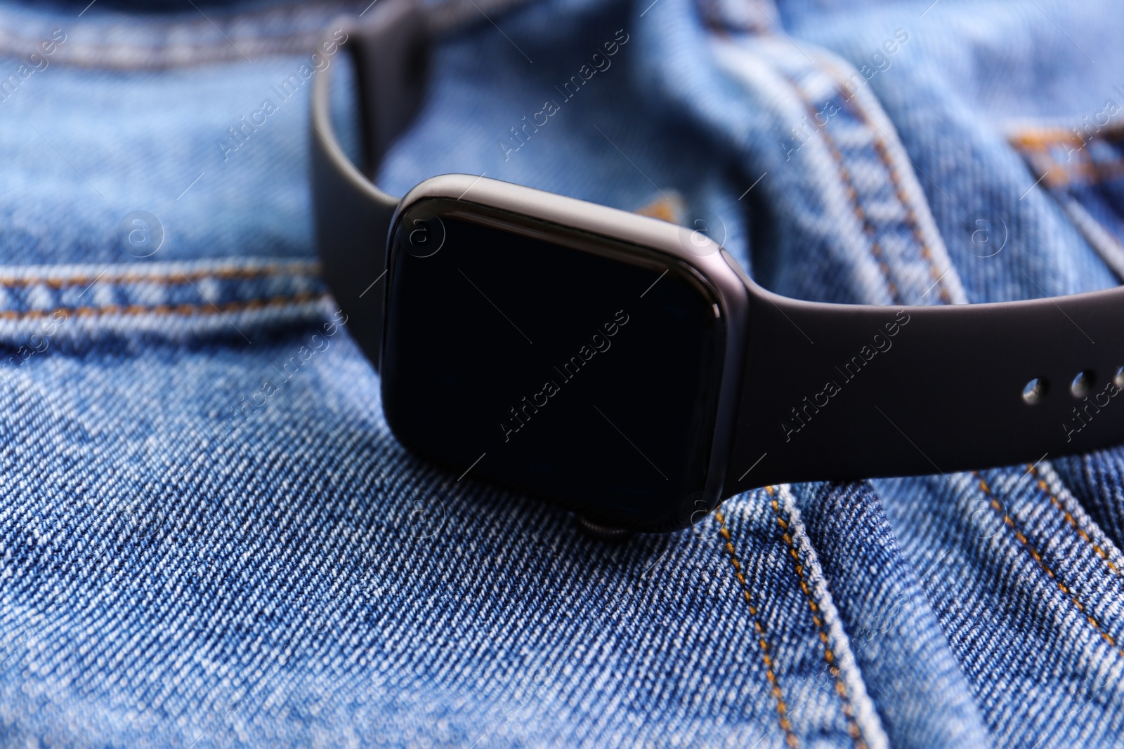 Modern stylish smart watch on jeans, closeup Photo of Modern stylish smart watch on jeans, closeup