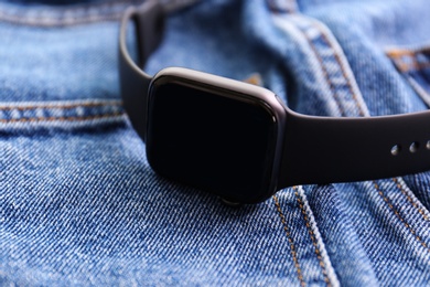 Photo of Modern stylish smart watch on jeans, closeup