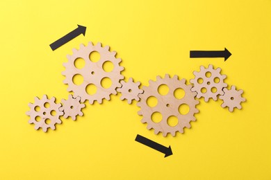 Photo of Business process organization and optimization. Scheme with wooden figures and arrows on yellow background, top view