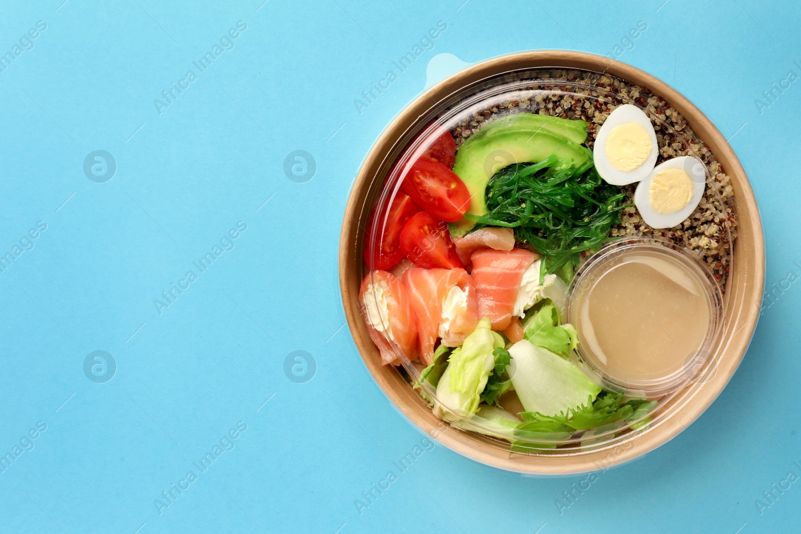 Photo of Tasty food in container on light blue background, top view. Space for text