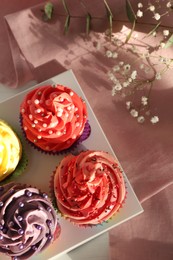 Photo of Delicious cupcake with bright cream on pink fabric