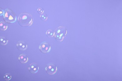 Photo of Many beautiful soap bubbles on violet background. Space for text