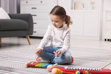 Photo of Little girl playing toy xylophone at home