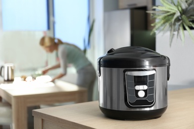 Modern multi cooker and blurred young woman on background, space for text