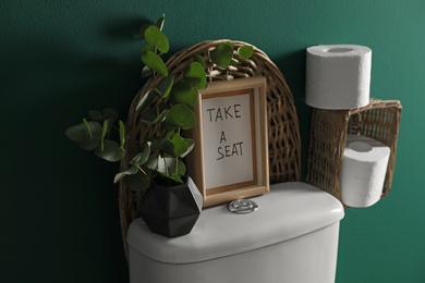 Photo of Decor elements, paper rolls and toilet bowl near green wall. Bathroom interior