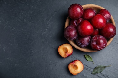 Delicious ripe plums on black table, flat lay. Space for text