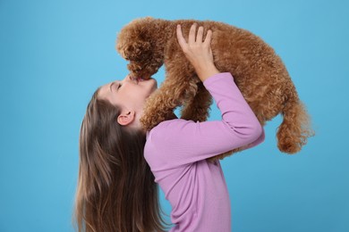 Photo of Little child with cute puppy on light blue background. Lovely pet