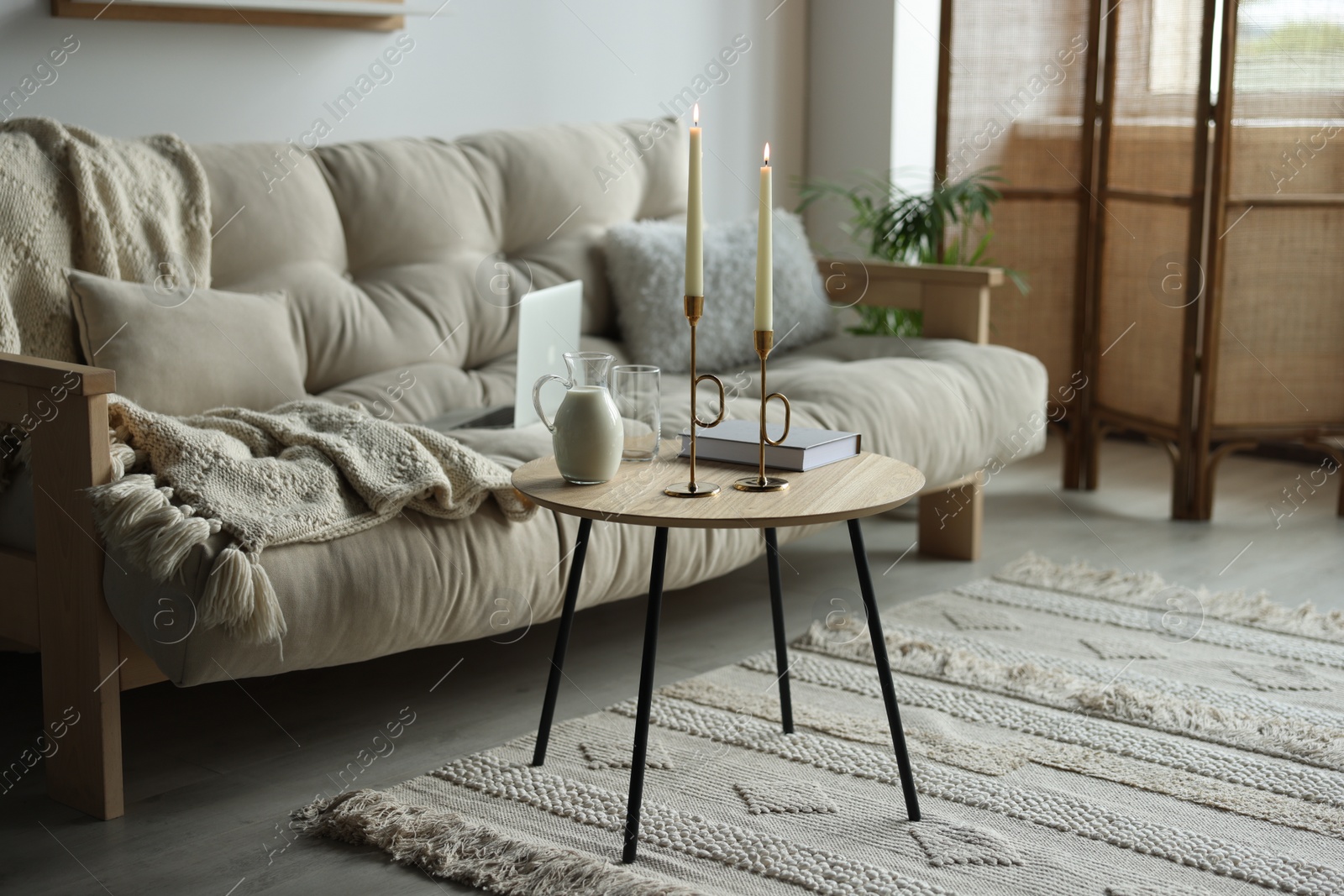 Photo of Modern living room interior with sofa, side table and candles