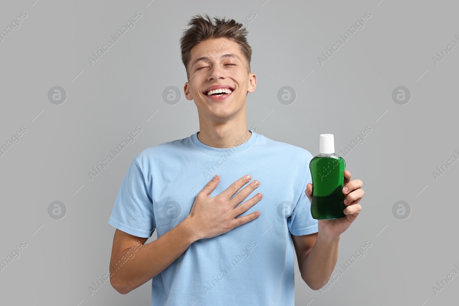 Photo of Young man with mouthwash on light grey background