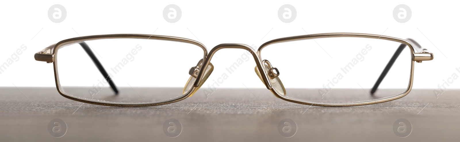 Photo of Stylish glasses with metal frame on table against white background