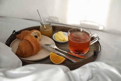 Photo of Tray with tasty breakfast on bed in morning