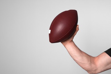 Photo of Man with American football ball on light grey background, closeup. Space for text